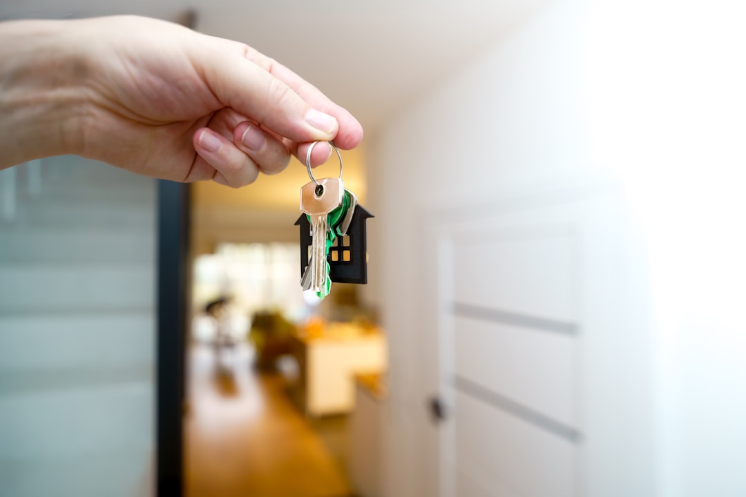 Person holding house keys in front of a new home entrance